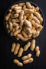Peanuts in shell. Groundnuts in bowl on black table. Top view.