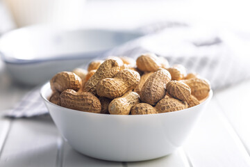 Peanuts in shell. Groundnuts in bowl on white table.