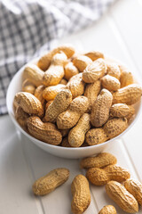 Peanuts in shell. Groundnuts in bowl on white table.
