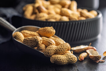 Peanuts in shell. Groundnuts in scoop on black table.