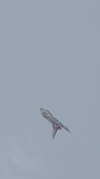Fast fighter jet during high speed combat maneuvers with clouds