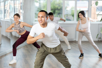 Smiling people practicing vigorous lindy hop movements in dance class