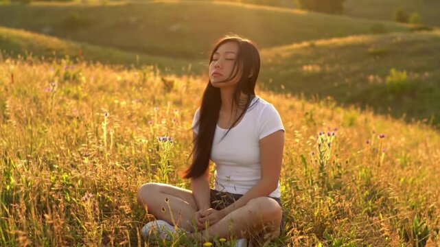 Jovem sentada em posicao de lotus no campo olhos fechados meditando e respirando