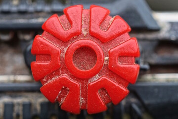 one plastic red screw is screwed into a black panel in a structure