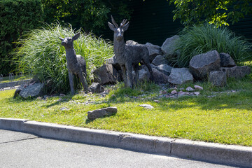 Two deer sculptures in landscaped garden with rocks and grass