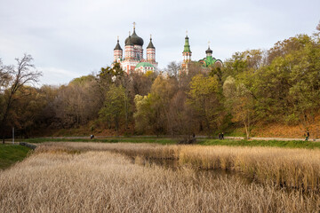 Orthodox church with domes on a hill above autumn park and pond