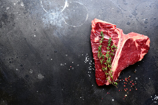 Raw organic T-bone steak with spices. Top view with copy space.