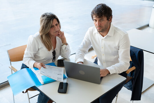 Two people in a meeting, financial advisor explaining investment options to a mature female client at a table