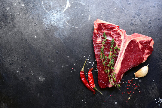 Raw organic T-bone steak with spices. Top view with copy space.