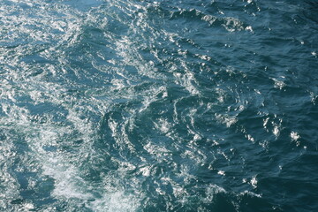 Deep blue ocean surface with white-capped ripples and waves catching sunlight