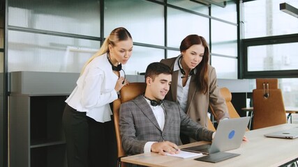 Consultants assist a sales agent in a modern office while providing client support using laptops and headphones during a collaborative work session - Powered by Adobe