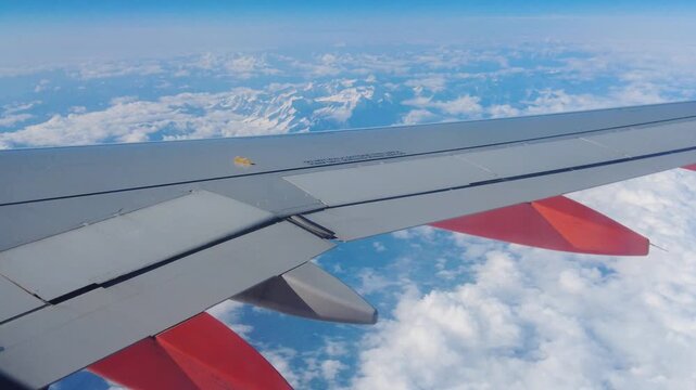 wing plane air above thick clouds distant snow capped mountains aeronautical detail high altitude landscape appear together closeup airplane sky flight horizon perspective 