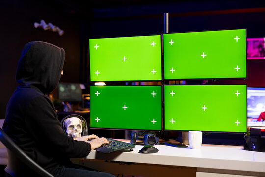 Hacker doing ransomware attacks using isolated screen multi monitor setup to hold company systems hostage and demand money. Man using chroma key computer, hacking enterprise networks, encrypting files