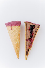 Whole and sliced berry chocolate ice cream cone on white background, minimalist food concept