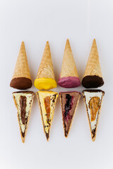 Assorted ice cream cones and slices with colorful toppings on white background