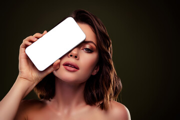 Elegant brunette woman holding a smartphone, showcasing beauty and fashion