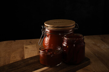 Homemade preserves in canning jars on wooden board