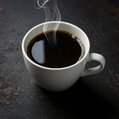 A white ceramic cup filled with black coffee, emitting steam. The cup is placed on a dark, textured surface.