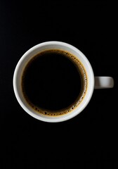 A top-down view of a white coffee cup filled with dark coffee, set against a black background.