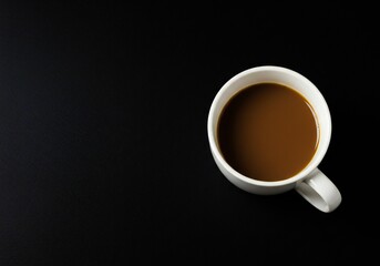 A white coffee mug filled with brown coffee sits on a dark surface. The composition is minimalistic, emphasizing the mug and its contents.