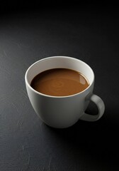 A white ceramic cup filled with coffee is placed on a dark textured surface. The scene captures the cup at a slight angle, emphasizing its shape and the rich color of the coffee.