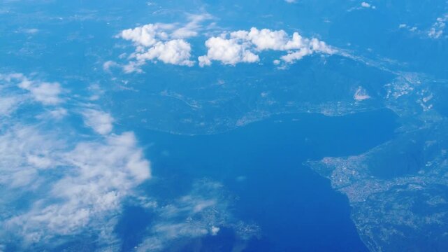 blue landscape tones dominate mountains lakes valleys below airplane while clouds floating add textural variation from aerial view perspective structure civilization 