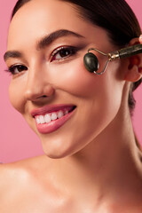 Gorgeous young woman using a jade roller on her face, showcasing beauty and selfcare practices