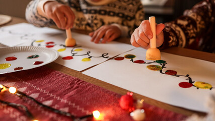 Children painting Christmas lights on paper at a festive holiday table