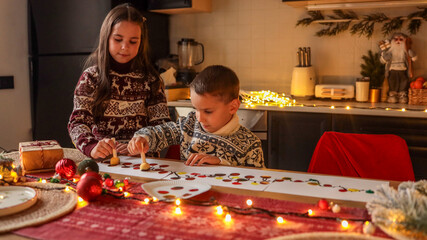 Children painting Christmas lights on paper at a festive holiday table