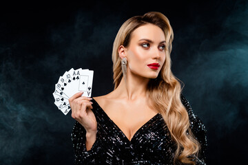 Elegant woman in a glamorous sequined dress holding playing cards with a confident expression