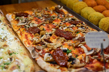 Authentic Italian pizza in a restaurant display window in Rome, Italy.  Different type of traditional Roman styple pizza . 