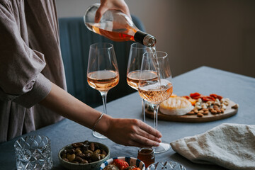 Pouring rose wine with classic snacks of cheese, bread and olives. Party or anniversary celebration.