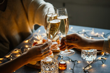 Friends celebrating Christmas or New Year eve party with champagne or sparkling wine.