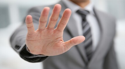 Obraz premium Business professional displays an outstretched hand signal indicating a request to halt or refuse something