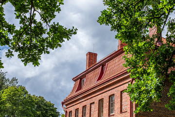 Renovated building with terracotta clay tiles and a warm ambiance, surrounded by lush greenery and a dramatic sky, showcasing the beauty of architectural renewal