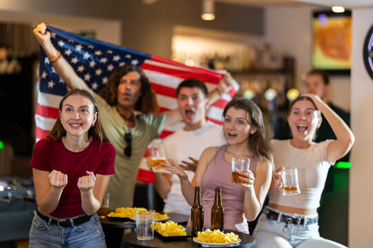 Group of fans of the United States national team spend time in a bar, shouting chants, supporting their favorite team