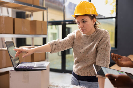 Staff members ensuring accurate order processing on a laptop, checking stock inventory in a small scale depot. Supporting e-business services with retail shipment and in house quality control.