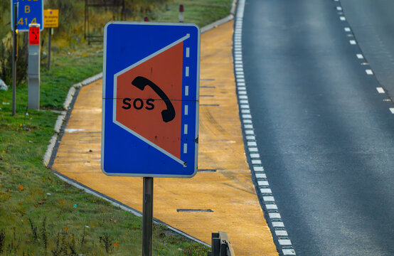 Controversial refuge on a SMART motorway where there is no hard shoulder. Yellow safety refuse with large SOS sign on an empty motorway with no cars.