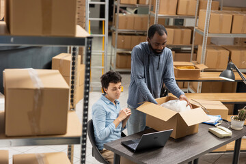 Multiethnic employees team checking the delivery logistics of a small business, developing local brand. Industrial depot space shows active logistics coordination and inventory tracking.