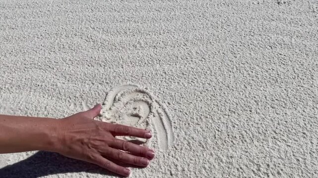 White Sands National Park in New Mexico. Hand plays with white gypsum crystals. Wave ripple pattern in white sand. 