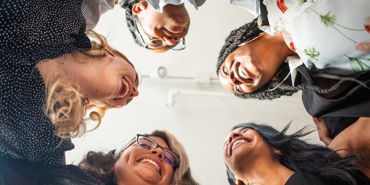 Diverse group of women in a circle, smiling and bonding. Women from various ethnic backgrounds sharing a joyful moment, emphasizing unity and diversity. Happy divers women in circle.