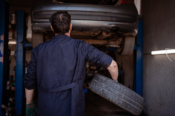 Mechanic changing tire in auto repair shop on a busy workday afternoon