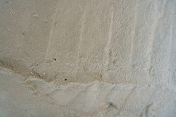 Footprints and tire tracks in fresh sand near a coastal area during low tide on a sunny day