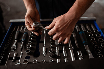 Hands carefully organizing tools in a mechanics toolbox during a workshop session