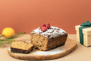 Chocolate Christmas cake with raspberries and sugar powder on wooden board. Closeup