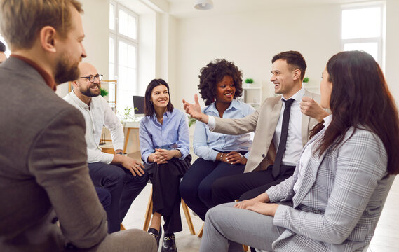 Multinational group of office colleagues engaging in a work meeting or presentation. Teamwork, discussion, and professional conversation in a modern office setting, between business people team.