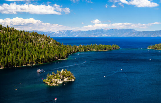 High-angle view of iconic Emerald Bay and Fannette Island in Lake Tahoe. Boats, including a tour ship, cruise on the deep blue water under a cloudy sky. Represents summer vacation and nature landmarks - Powered by Adobe