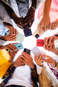 Low angle view of young group of student people using smart phones together outside. Business, social media and communication lifestyle concept