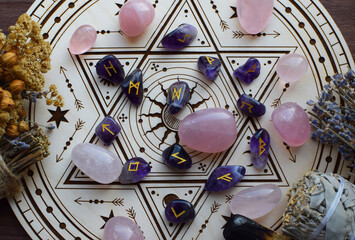 Rose quartz crystals and Scandinavian runes made from natural amethyst, along with dried lavender herbs, on a wooden altar for divination. Divination, witchcraft, and spiritual esoteric practice.