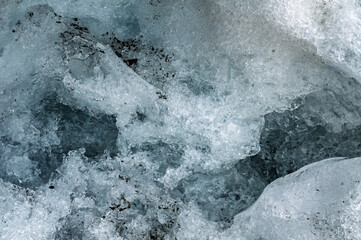 Turquoise glacial ice forming intricate abstract shapes revealing layered blue and white textures within frozen winter wilderness landscape